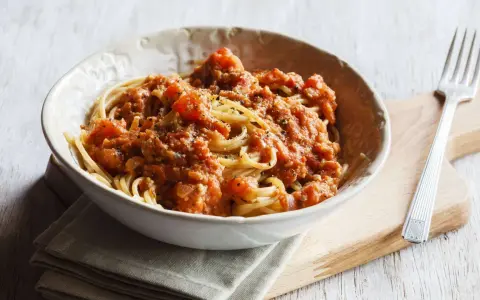 Eine Schüssel Spaghetti mit einer herzhaften, tomatigen Bolognese-Sauce, perfekt für eine schnelle Mahlzeit.