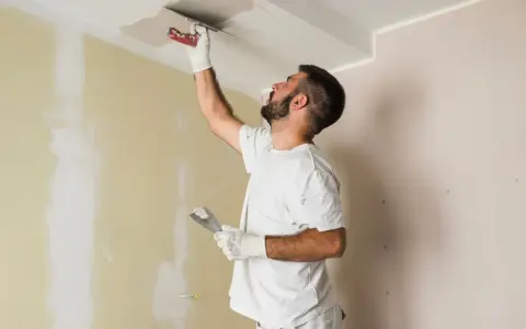 Hombre aplica mortero sobre techo pintado. Se puede aplicar mortero sobre pintura para reparaciones.