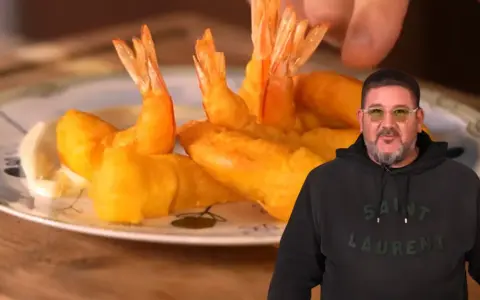 Un hombre sonriente muestra un plato de gambas a la gabardina doradas y crujientes, listas para disfrutar.