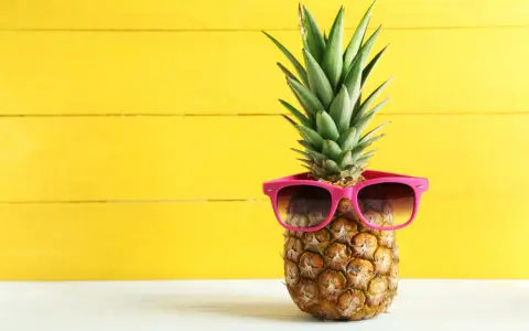 Ananas w okularach przeciwsłonecznych na żółtym tle. Czy wiesz, jaki ananas indeks glikemiczny ma dla Twojej diety?