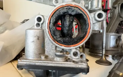 Stark verschmutzte Drosselklappe, ein deutliches Zeichen für drosselklappe defekt symptome. Rußablagerungen blockieren den Luftstrom.