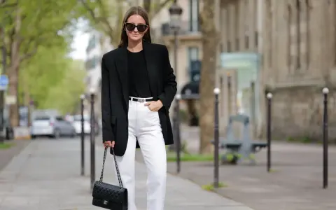 Donna con blazer nero, jeans bianchi e borsa Chanel, un look che aiuta a sembrare più alto.