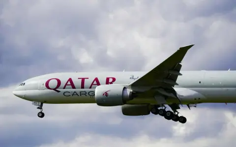 Samolot Qatar Airways Cargo z wysuniętym podwoziem, gotowy do lądowania. W tle chmury.