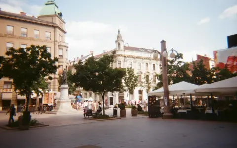 Spacer z kawiarnianymi stolikami i ludźmi, uchwycony aparatem Kodak M35.