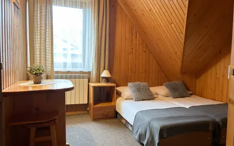 Pokój w stylu góralskim, idealny na wypoczynek u Lucyny Białka Tatrzańska. Dwa łóżka, drewniane meble i przytulna atmosfera.