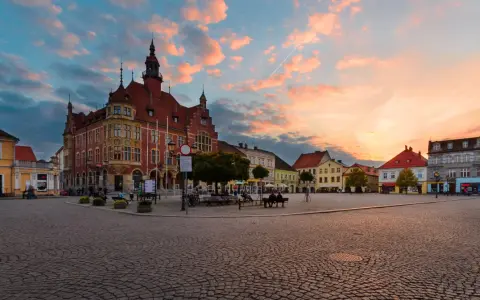 Rynek w Tarnowskich Górach o zachodzie słońca. Kolorowe chmury nad zabytkową zabudową i brukowanym placem.