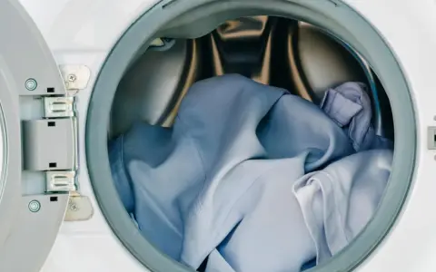 Blaue Wäsche in einer offenen Waschmaschine. Die Frage, ob Polyester einlaufen kann, beschäftigt viele.