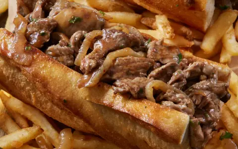 Un delicioso pepito de ternera jugoso, relleno de tiernos trozos de carne y cebolla caramelizada, acompañado de crujientes patatas fritas.