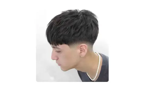 Joven con corte de pelo moderno, un low fade hombre con la parte superior texturizada y flequillo recto.
