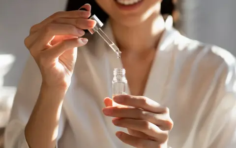 Kobieta aplikuje serum z kwasem fitynowym, dbając o swoją cerę.