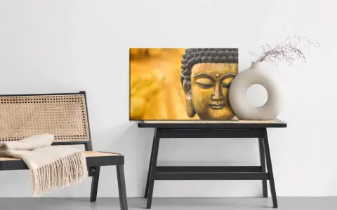 Buddha-tavla med matt material bredvid en stol med pläd och ett bord med en vas.