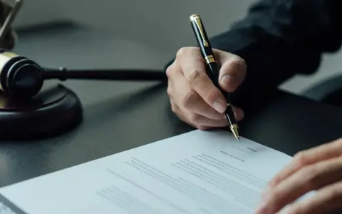 Sądowy młotek i dłoń pisząca dokument. Sprawa dotyczy wydziedziczenia a zachowku.