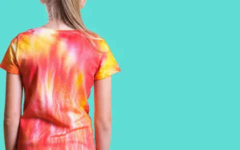 Dziewczynka w koszulce tie dye w odcieniach czerwieni i żółci.