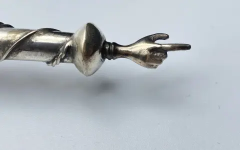 Manico in argento 325, cosa significa? Un dettaglio di un oggetto con una mano che indica.