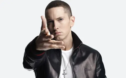 Eminem w czarnej skórzanej kurtce i białej koszulce, z ręką wyciągniętą w stronę widza.