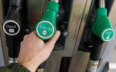 Dłoń trzymająca zielony pistolet z napisem "Euro 95 E10", obok pistolety na Diesel i Super+ 98.