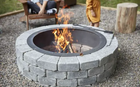 A stone fire pit with a roaring fire, perfect for a backyard gathering. This image shows how to build a fire pit for cozy evenings.