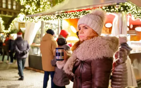 Frau mit Becher auf dem **Weihnachtsmarkt Nottuln**, umgeben von Lichtern und Menschen.