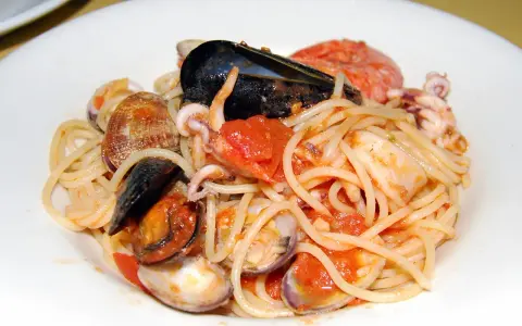 Spaghetti allo scoglio con cozze, vongole, calamari e pomodoro. Un piatto di mare ricco e saporito.