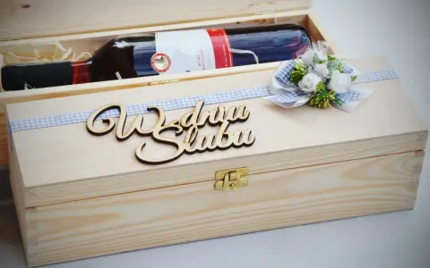 Drewniana skrzynka z butelką wina, ozdobiona wstążką i napisem "Wszystkiego najlepszego z okazji ślubu". Oryginalny prezent na ślub zamiast kwiatów.