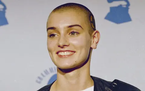 Uśmiechnięta Sinéad O'Connor z ogoloną głową, w czarnej ramonesce. Jej spojrzenie mówi, że nic nie porównuje się do Ciebie.