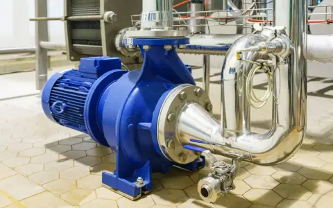 Pompe à eau industrielle bleue, connectée à des tuyaux en acier inoxydable. Un système essentiel pour gérer la pression eau maison.