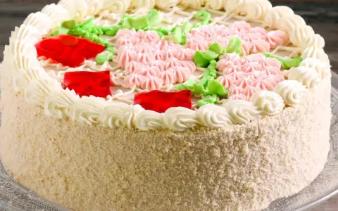 Kolorowy tort z kremem, galaretką i kwiatkami z kremu. Idealny, by czym przełożyć tort dla dzieci na przyjęcie.