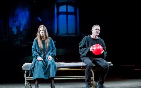 Agata Kulesza w teatrze, siedzi obok mężczyzny z czerwoną piłką.