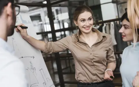 Mujer sonríe mientras explica un gráfico en un rotafolio, demostrando cómo liderar equipos con éxito.