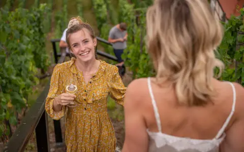 Lachende junge Frau mit Weinglas im Weinberg an der Saale-Unstrut.