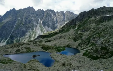 Dwa górskie jeziora odbijające niebo w sercu słowackich Tatr, otoczone skalistymi zboczami i zielenią.