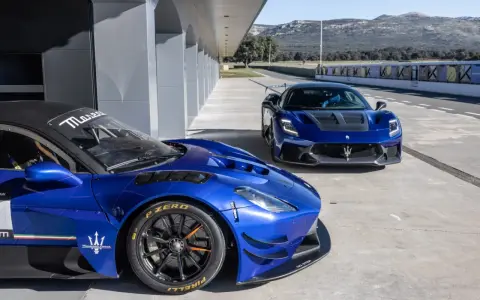 Dwa niebieskie Maserati na torze wyścigowym. Jedno z nich, z bliska, ma na oponach napis Pirelli P Zero.