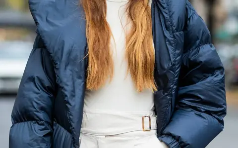 Outfit maestra asilo: piumino blu, dolcevita beige e pantaloni chiari con cintura.