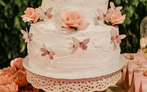 Gâteau à étages décoré de roses et de papillons, recouvert d'une délicate crème au beurre.