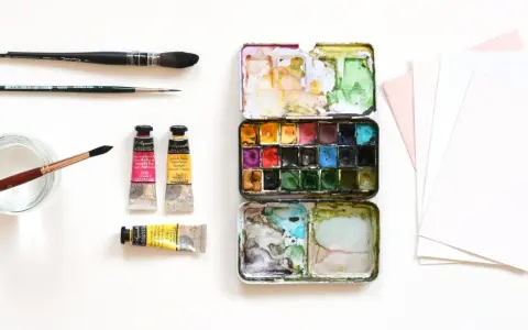 Matériel d'artiste : palette de peinture, tubes de couleur, pinceaux et papier pour le support aquarelle.