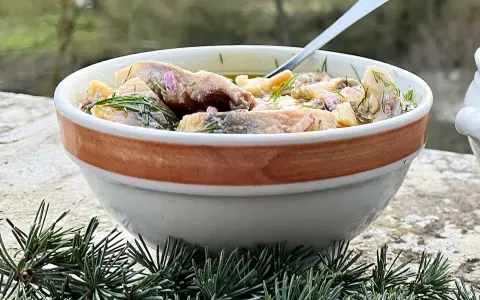 En skål med inlagd sill, dill och blommor. Perfekt för ett svenskt midsommarfirande eller som en del av ett inlagd sill recept.
