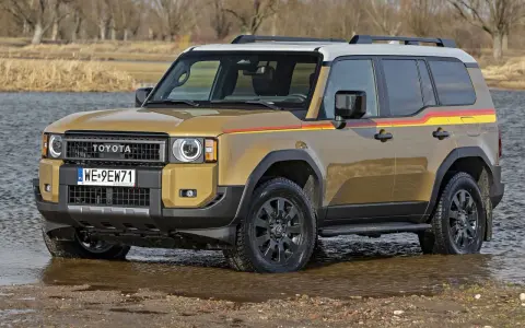 Złoty Toyota Land Cruiser Prado z kolorowymi pasami na boku, wjeżdża do wody.