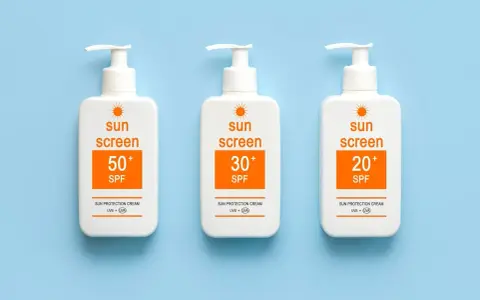 Trois bouteilles de crème solaire avec des indices SPF variés (50+, 30+, 20+). Le SPF signification est la protection contre les rayons du soleil.