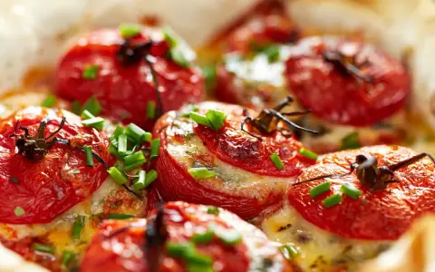 Pomodori ripieni al forno, dorati e succosi, con formaggio fuso e erba cipollina. Un'idea gustosa per un antipasto o un contorno.