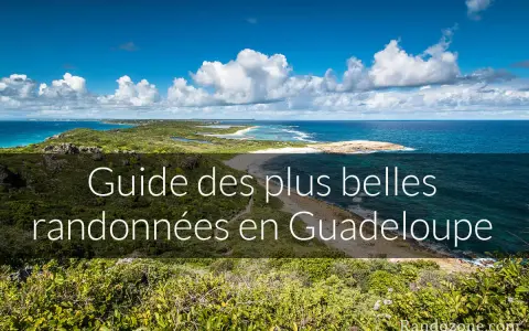 Paysage côtier luxuriant avec la mer bleue et des nuages blancs. Ce guide des plus belles randonnées en Guadeloupe vous invite à explorer ses montagnes verdoyantes.