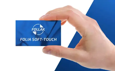 Dłoń trzyma kartę z napisem "Folia Soft-Touch" od FOLLAK, prezentując efekt laminacji.