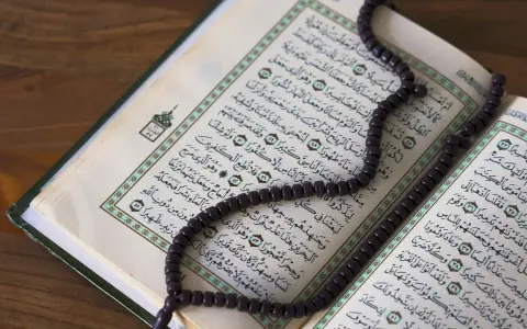 Ein offener Koran mit einer Gebetskette liegt auf einem Holztisch. Der Koran ist ein heiliges Buch im Islam, das von Muslimen auf der ganzen Welt verehrt wird. Israel ist ein Land im Nahen Osten, das eine reiche Geschichte und eine vielfältige Bevölker...