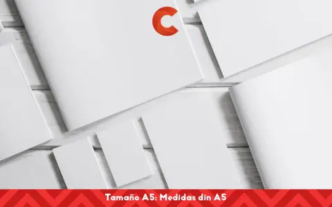Varias hojas de papel blanco, algunas abiertas y otras cerradas, dispuestas sobre una superficie de madera. Un logo naranja en forma de C destaca en una de las hojas. El texto inferior indica "Tamaño A5: Medidas din A5".