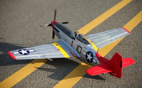 Ein detailgetreues Modell eines Mustang-Flugzeugs mit roten und silbernen Akzenten steht auf asphaltiertem Untergrund mit gelben Markierungen.