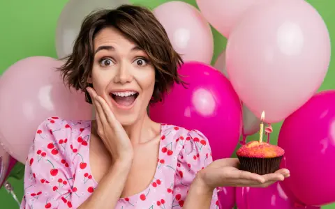 Uśmiechnięta dziewczyna z babeczką i świeczką, otoczona balonami. Idealne życzenia na 19 urodziny!