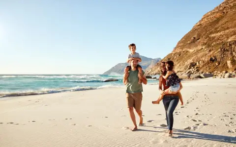 Glad familj på stranden. För att undvika att smittas av hepatit b, undvik delade personliga föremål.