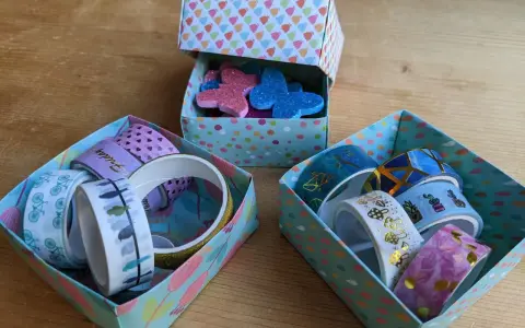 Bunte schachtel falten mit deckel, gefüllt mit Washi-Tapes und Glitzer-Schmetterlingen.