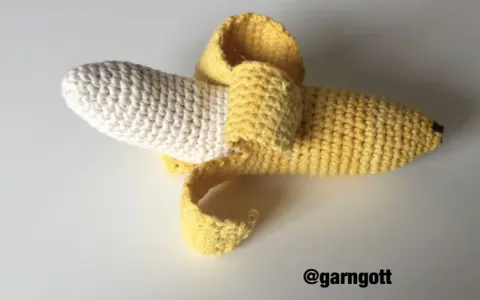 En virkad banan med skalet delvis avdraget. Den vita delen är bananen, och det gula är skalet.
