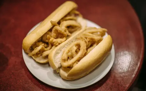 Dos bocadillos de calamares fritos en pan blanco sobre un plato blanco.