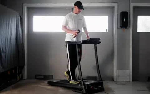 Man med keps tränar på löpband, siktar på att springa 5 km på 30 min.